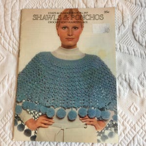 May include: A vintage book cover titled "SHAWLS & PONCHOS" featuring a woman wearing a blue crocheted shawl with pom-pom trim. The cover also includes the text "COATS & CLARK'S BOOK No. 207" and the price "35c".