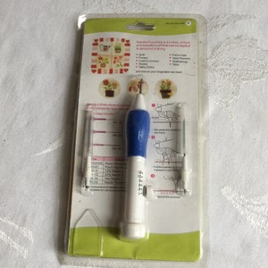 Könnte beinhalten: Ein weiß-blaues Nadel-Stanzwerkzeug mit einer Nadel und einer Tiefenlehre. Das Werkzeug ist in einer durchsichtigen Kunststoff-Blisterverpackung mit Anleitung und einer Tabelle mit Nadelgrößen verpackt. Die Verpackung zeigt eine Vielzahl von Bastelprojekten, die mit dem Werkzeug hergestellt werden können, darunter Quilts, Handtaschen, Kissenbezüge, Handtücher, Tischdecken, Platzsets, Tischläufer, Wandbehänge und Einkaufstaschen.