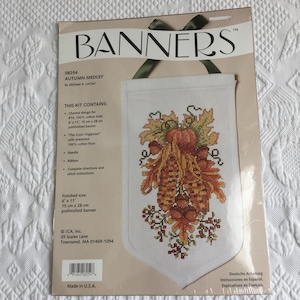 Puede incluir: Un kit de punto de cruz para un banner con temática otoñal. El banner presenta un diseño de hojas de otoño, calabazas y maíz. El kit incluye un banner preacabado, hilo, una aguja e instrucciones. Tamaño final: 15 cm x 28 cm.