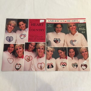 May include: Two books of iron-on patterns for fabric, wood, and tin. The book on the left is titled "The Heart of Country" and the book on the right is titled "American Heartla". Both books feature images of women wearing sweaters with heart-shaped designs.