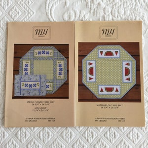 May include: Two paper foundation patterns for table mats. The first pattern is for a spring flower table mat, measuring 16 3/4 inches by 16 3/4 inches. The second pattern is for a watermelon table mat, also measuring 16 3/4 inches by 16 3/4 inches. Both patterns are from MH Designs.