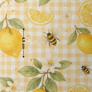 May include: A yellow and white gingham fabric with a repeating pattern of lemons, bees, and flowers. The lemons are yellow with a slight green tint and the bees are brown and yellow. The flowers are white with a yellow center. The fabric is 4.5 inches wide.