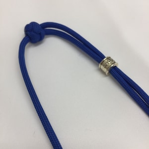 May include: A blue paracord necklace with a silver bead featuring a Celtic knot design.