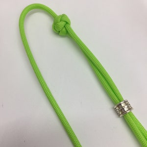 May include: A lime green paracord cord with a knot at one end and a silver bead at the other end.