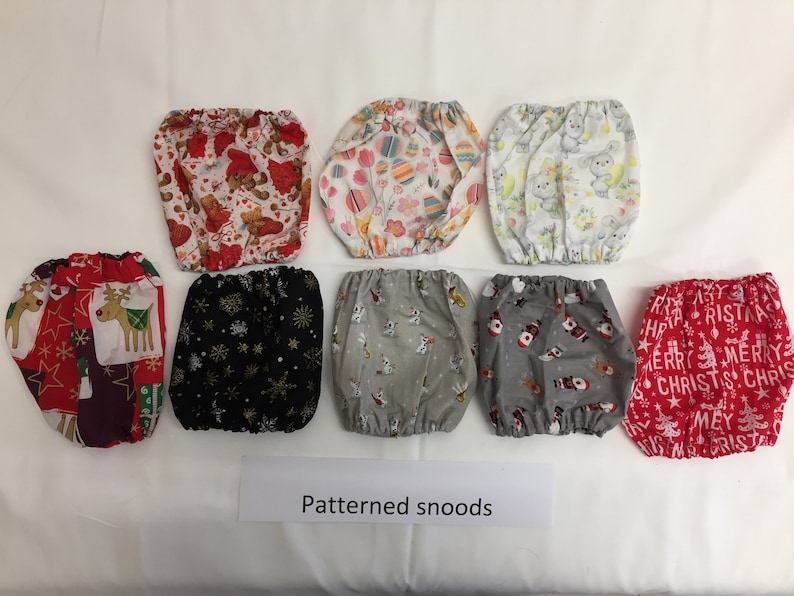 May include: A collection of patterned snoods, each with a unique design. The snoods feature various festive patterns, including Christmas themes with reindeer and snowmen, and other designs with bears, eggs, and snowflakes. The text "Patterned snoods" is visible.