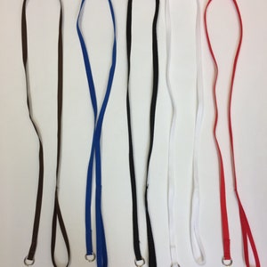 Puede incluir: Cinco cordones de diferentes colores con anillos metálicos en los extremos. Los cordones son marrón, azul, negro, blanco y rojo.