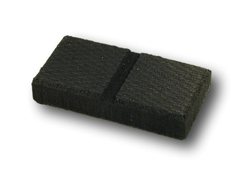 May include: A black charcoal briquette with a groove down the center.