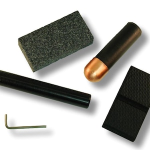May include: A set of tools for sharpening a stylus pen. The set includes a black stylus, a black and gray sharpening stone, a black sharpening block, a copper-colored tip, and a small silver allen wrench.