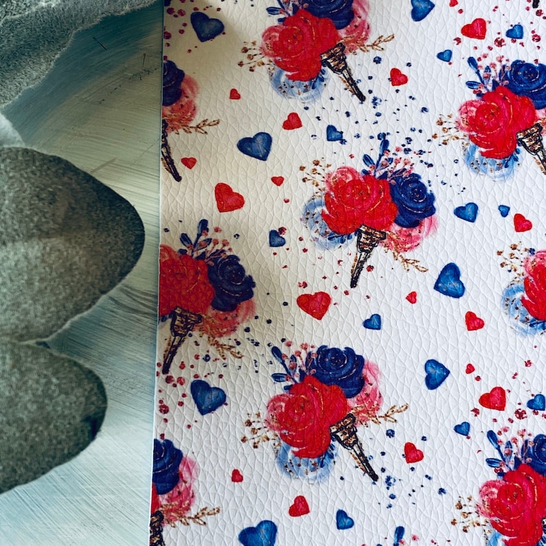 May include: White patterned material featuring bouquets of red and blue roses, blue hearts, and gold accents. The design is repeated across the surface. The material has a textured appearance.