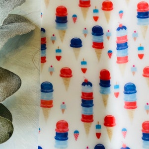 May include: A white background is covered with a repeating pattern of ice cream cones in red, white, and blue. The cones vary in size and style, some with cherries on top. The design evokes a festive, summery feel.
