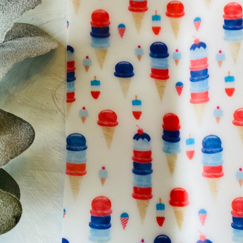 May include: A white background is covered with a repeating pattern of ice cream cones in red, white, and blue. The cones vary in size and style, some with cherries on top. The design evokes a festive, summery feel.