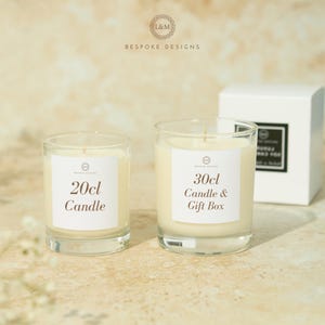 May include: Two glass candles with white labels, one labeled "20cl Candle" and the other "30cl Candle & Gift Box." A white gift box is in the background. The candles have a cream-colored wax and are set against a neutral background.