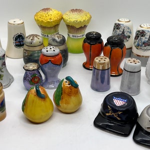 Peut inclure: Une collection de 20 salières et poivrières vintage. Les salières sont en céramique et présentent une variété de motifs, notamment des motifs floraux, en forme de poire et sur le thème des États. Certaines salières ont des accents dorés.