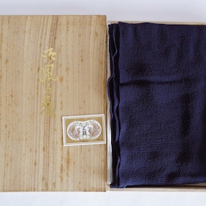 Può includere: Una scatola di legno con un tessuto blu scuro all'interno. La scatola ha un'etichetta dorata con caratteri giapponesi e un'etichetta più piccola con un'immagine di due pavoni.