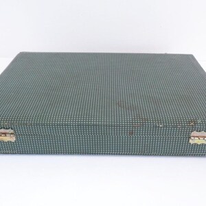 May include: A rectangular, vintage case with a teal and white polka dot pattern. The case has metal hinges and a clasp. The corners show signs of wear. The case is likely for storing flatware or other items.