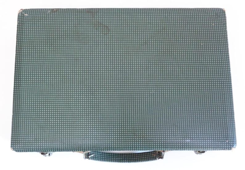 May include: A vintage green briefcase with a repeating white dot pattern. The briefcase has a handle and metal clasps. The exterior shows signs of wear, suggesting it is a used item.