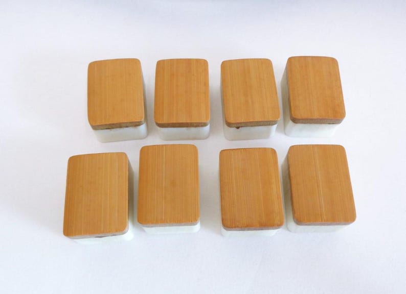 May include: Eight rectangular containers with light brown bamboo lids and white bases are arranged on a white surface. The lids have a natural wood grain, and the containers are evenly spaced.
