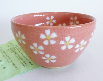 May include: A small pink ceramic bowl with a crackled glaze and white floral pattern. The bowl is approximately 4 inches in diameter.