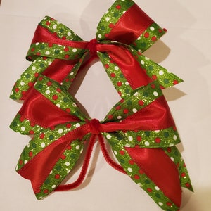 May include: Two red and green Christmas bows with white polka dots and glitter. The bows are tied together with a red velvet ribbon.