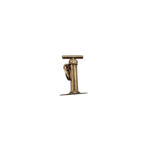 May include: A gold-toned metal charm shaped like a vintage hand pump. The charm features a vertical cylindrical body with a horizontal handle at the top and a flat circular base at the bottom. A small jump ring is attached to the side of the pump.