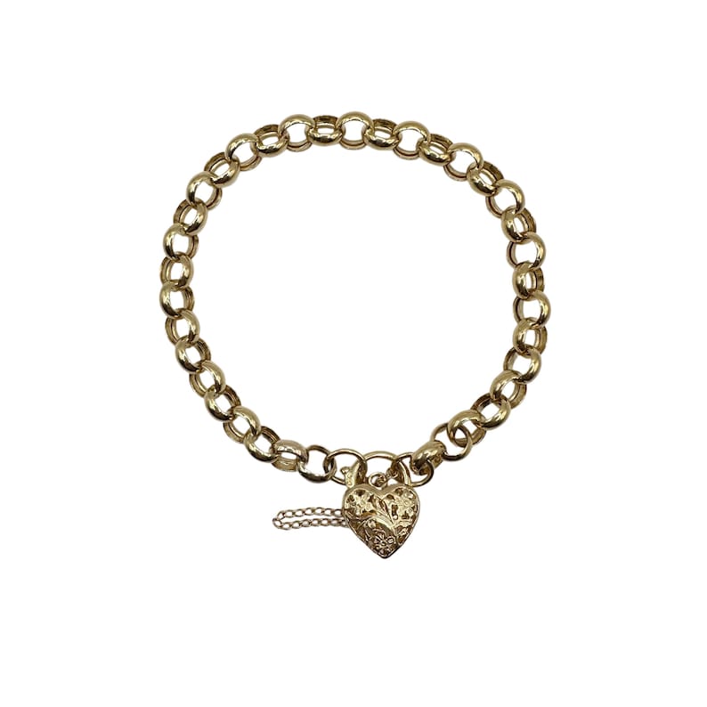 Op de afbeelding: Goudkleurige kettingarmband met een hartvormige hangslot sluiting. De armband heeft een reeks afgeronde schakels. De hartvormige sluiting heeft een sierlijk bloemmotief en een kleine ketting. Op een witte achtergrond.