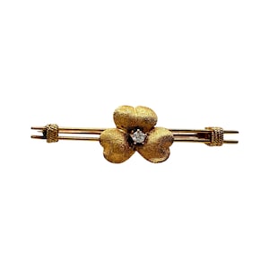 May include: A gold brooch with a textured flower design and a single diamond in the center.