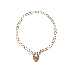 May include: A gold-colored chain bracelet with a heart-shaped padlock clasp. The bracelet features a series of oval links forming a circular shape. The heart-shaped padlock has a keyhole and decorative details.