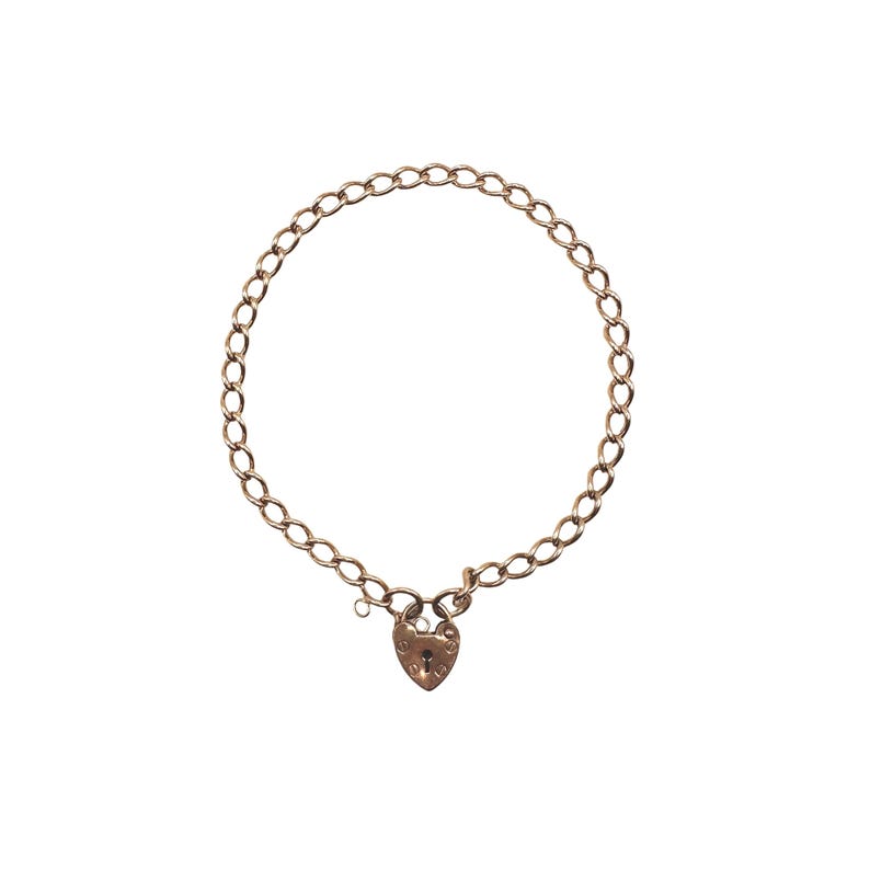 May include: A gold-colored necklace with a heart-shaped padlock clasp. The chain is made of oval links. The necklace is displayed on a white background. The padlock has a keyhole and decorative details.