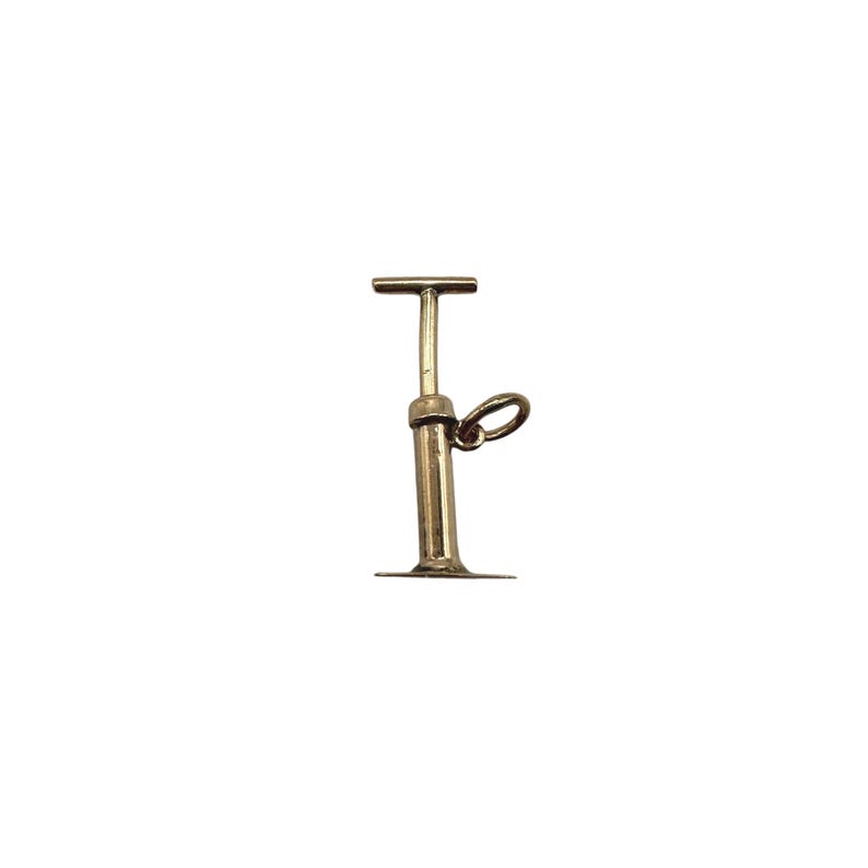 May include: A gold-toned metal charm shaped like a manual air pump. The charm features a vertical cylindrical body with a flat base, a T-shaped handle at the top, and a small circular jump ring attached to the side for hanging on a chain or bracelet.