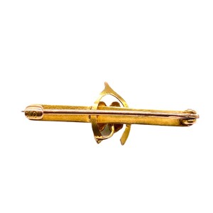 May include: A gold-toned brooch with a swirling design. The brooch has a pin on the back for attaching to clothing.
