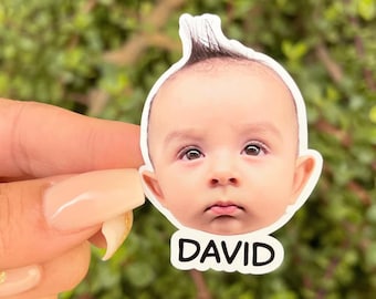 May include: A white sticker with a photo of a baby with a spiky hairstyle. The sticker has the name "DAVID" printed below the photo.