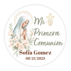 May include: Round sticker with a watercolor illustration of a woman in a white veil, praying. The text "Mi Primera Comunion" is written in green script, with the name "Sofia Gomez" and the date "08/25/2023" in brown.
