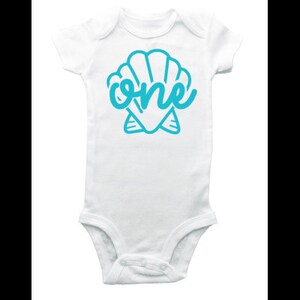 May include: White baby onesie with a blue seashell and the word "one" inside the shell.
