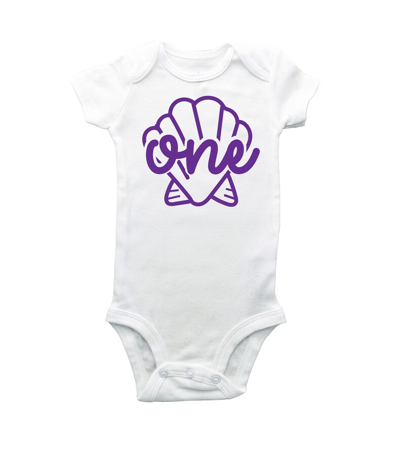 May include: White baby onesie with a purple seashell and the word "one" inside the shell.
