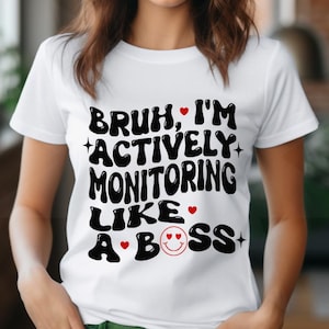 Peut inclure: T-shirt blanc avec un texte noir qui dit "Bruh, I'm actively monitoring like a boss" avec des cœurs rouges et un visage souriant.