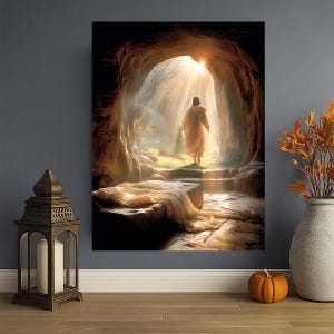 May include: An artistic print shows a figure in a white robe exiting a cave, illuminated by sunlight. The scene includes a stone tomb with draped fabric, suggesting a religious theme. The artwork is displayed on a wall with decorative elements.