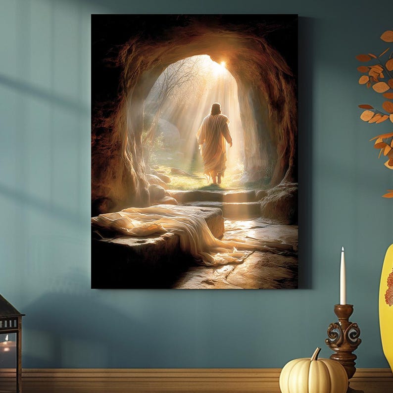 May include: A canvas print showing a figure in a white robe exiting a cave, illuminated by sunlight. The artwork uses a warm colour palette with detailed textures, creating a peaceful and spiritual scene. The image is mounted on a wall.