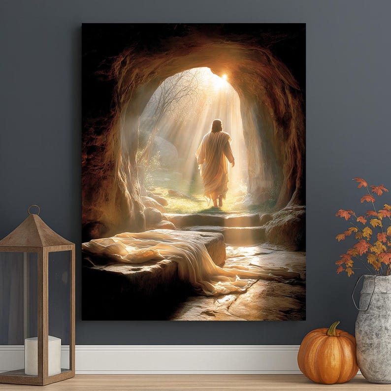 May include: A religious art print shows a figure in a white robe emerging from a cave into bright sunlight. The artwork features a stone tomb with draped fabric, steps, and a natural outdoor setting. The overall colour palette is warm, with golden and brown tones.
