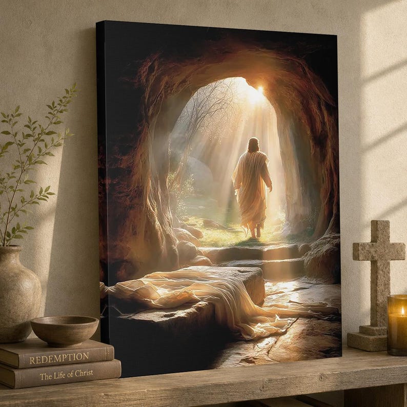 May include: A canvas print showing a figure in a white robe exiting a cave, illuminated by sunlight. The image features a stone tomb, steps, and bright light, with the text "Redemption" and "The Life of Christ" on a book.