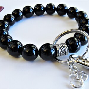May include: Black onyx beaded bracelet with a silver key ring and a charm with the number 33.