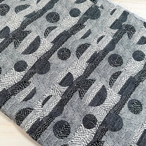 Puede incluir: Tela con estampado geométrico en blanco y negro con un diseño repetitivo de círculos, semicírculos y rayas.