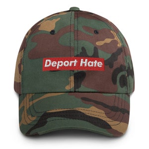 May include: A camouflage baseball cap with a red patch that says "Deport Hate" in white letters.