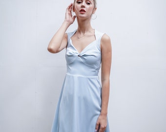 May include: A light blue sleeveless dress with a sweetheart neckline and a knotted detail at the bust. The dress has a fitted bodice and a flowing skirt.
