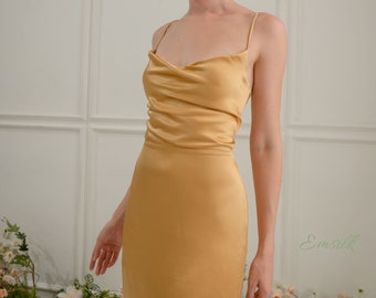 Könnte beinhalten: Eine Frau trägt ein goldenes Satin-Kleid mit einem Schalkragen und Spaghettiträgern. Das Kleid hat einen Schlitz an der Seite und eine figurbetonte Silhouette.