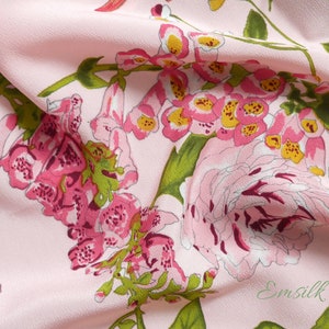 May include: Pink fabric with a floral print featuring pink, white, and yellow flowers. The fabric has a subtle texture and is draped over a surface.