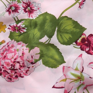 May include: Pink fabric with a floral print featuring pink, white, and green flowers. The fabric has a subtle sheen and a soft texture.