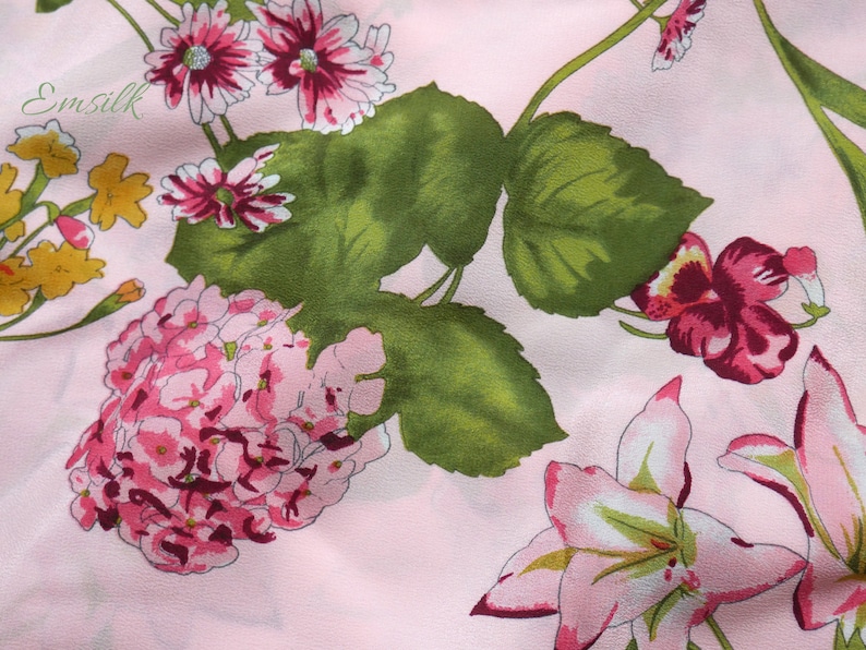 May include: Pink fabric with a floral print featuring pink, white, and green flowers. The fabric has a subtle sheen and a soft texture.