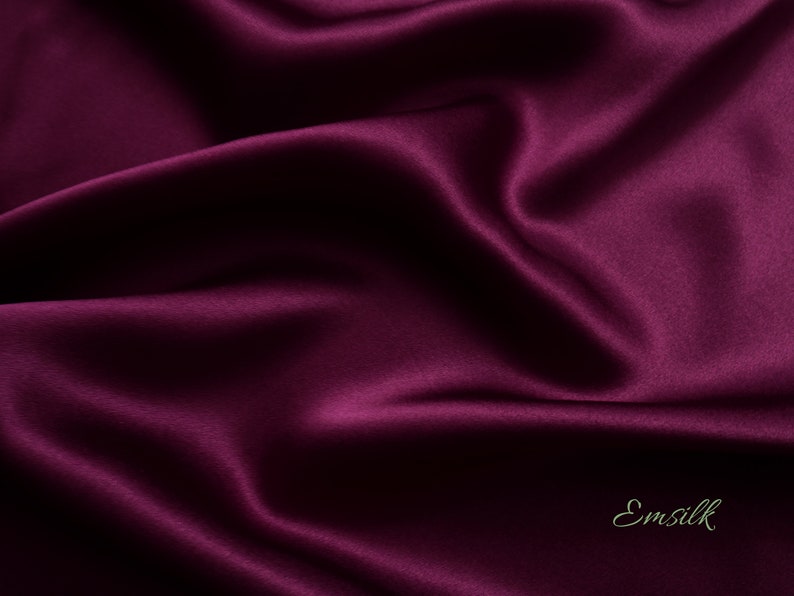 May include: Close-up of a deep purple satin fabric with a subtle sheen. The fabric is smooth and luxurious, with soft folds and wrinkles.