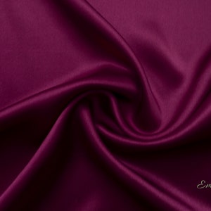 May include: Close-up of a deep burgundy satin fabric, showing the smooth, luxurious texture and subtle sheen.