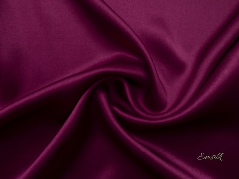 May include: Close-up of a deep burgundy satin fabric, showing the smooth, luxurious texture and subtle sheen.